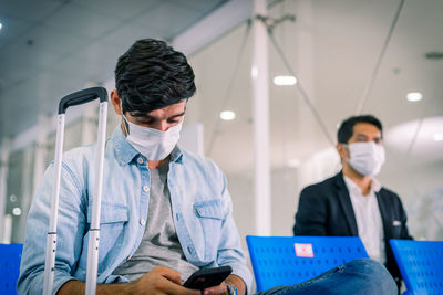 Men wearing mask sitting at airport