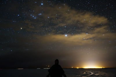 Rear view of silhouette man looking at sky at night