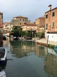 Canal amidst buildings in city against sky