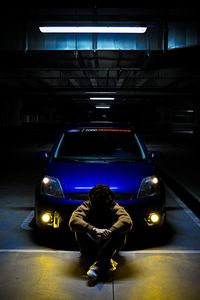 Man standing at illuminated parking lot