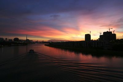 River in city against sky during sunset