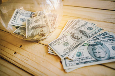 High angle view of paper currency in jar on wooden table