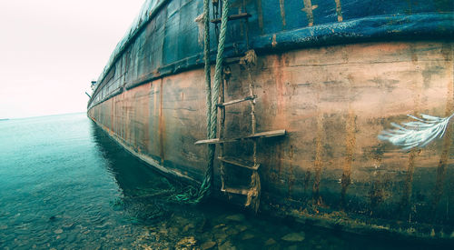 Abandoned ship in sea against sky