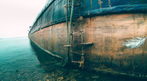 Abandoned ship in sea against sky