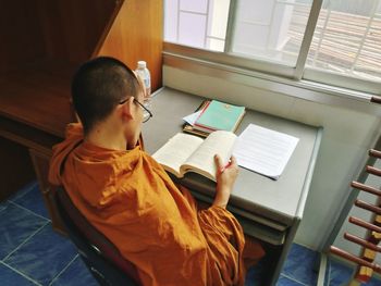 High angle view of monk reading book at home