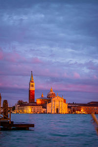 View of buildings at waterfront against cloudy sky