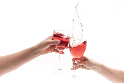 Cropped hand of person holding wineglass against white background