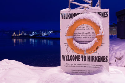 Yellow lifeguard ring over information sign by sea at night