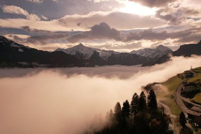 Scenic view of mountains against sky with sun breaking through clouds