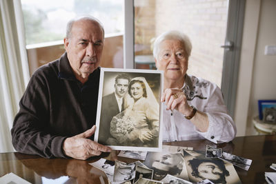 Senior couple showing their wedding photo at home