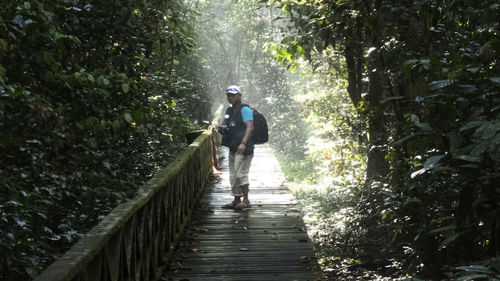 Rear view of man walking on footpath in forest