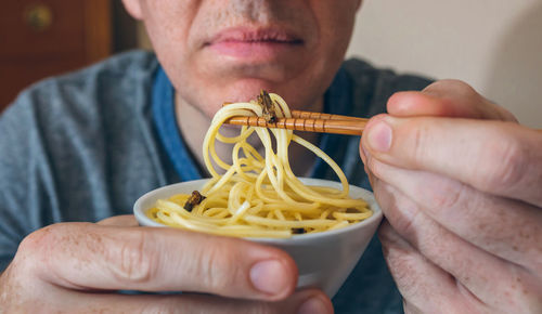 Midsection of man having noodles and worms in restaurant