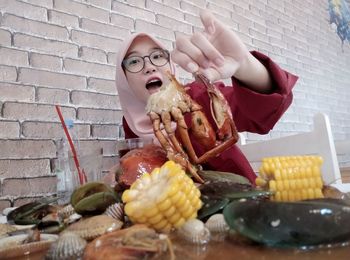 Low angle portrait of woman holding crab on table in restaurant