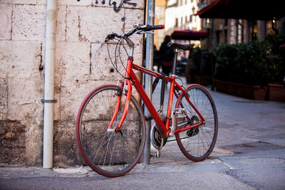 Bicycle leaning on wall by street