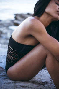 Black multiracial woman lifestyle portrait by the ocean in a swimsuit