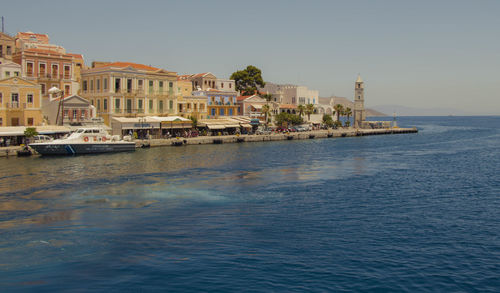 Buildings by sea against clear sky