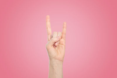 Close-up of human hand against pink background