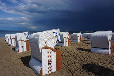 Hooded chairs on beach against sky