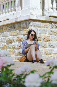 Portrait of young woman sitting on wall