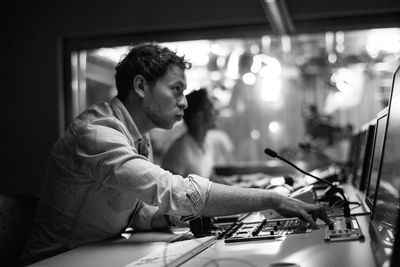 Side view of man using musical equipment in recording studio