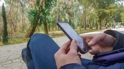 Close-up of man using mobile phone in park