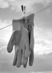 Low angle view of human hand holding rope against sky