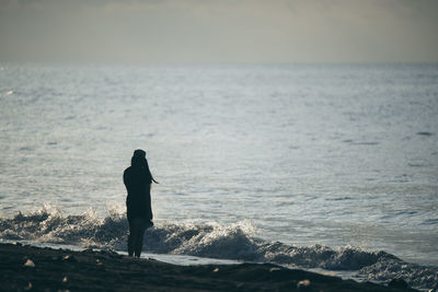 Rear view of silhouette man looking at sea against sky