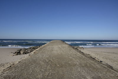 Scenic view of beach against clear blue sky