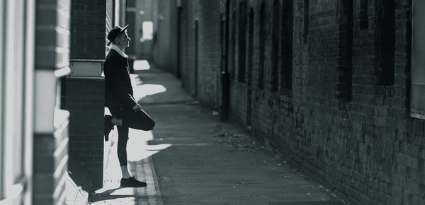 Profile view of man leaning on wall in alley