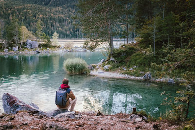 Man sitting on rock by river in forest