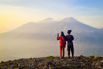 Friends standing on mountain against sky