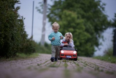 Rear view of boy playing with suitcase on field