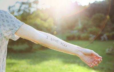 Cropped hand of man showing text written on forearm at park