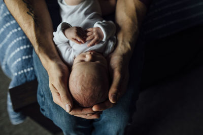 High angle view of father carrying sleeping daughter at home