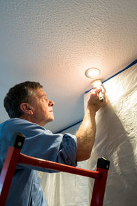 Low angle view of man painting ceiling