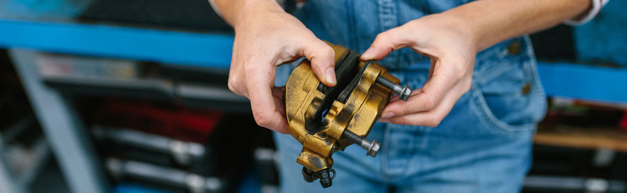 Mechanic woman checking caliper brake system on garage