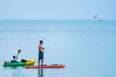 Men in boat on sea against sky