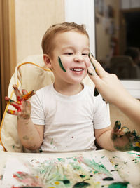 Boy playing with paint on high chair at home
