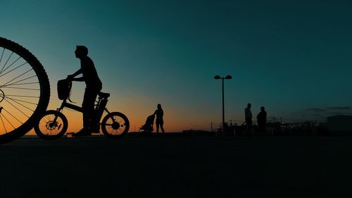 Silhouette man riding bicycle on road against sky