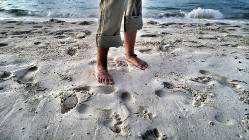 Low section of man standing on beach