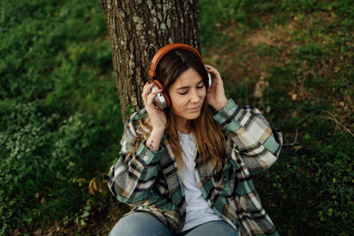 Portrait of teenage girl sitting on tree trunk in forest