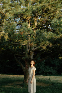 Portrait of woman standing by tree