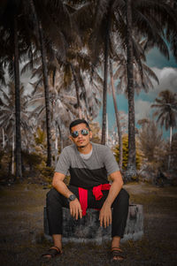 Portrait of young man wearing sunglasses in forest