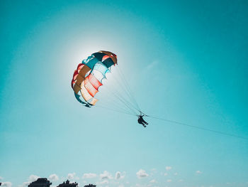 Low angle view of person paragliding against clear blue sky