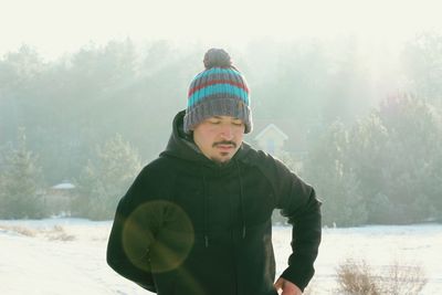 Young man standing on snow covered field during winter
