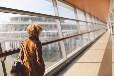 Rear view of man looking through window