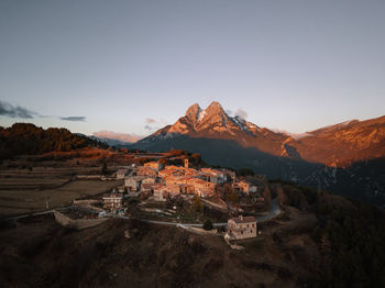 Aerial view of buildings and mountains against clear sky