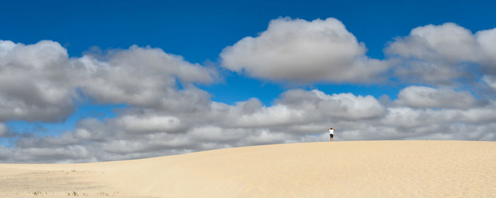 Panoramic shot of man on sand dune against sky