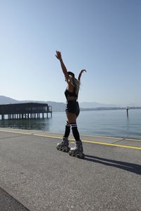 Woman inline skating on road by sea