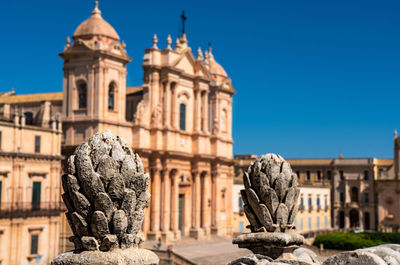  baroque stone decorations in the shape of a pine cone that frame the facade of the cathedral of noto 